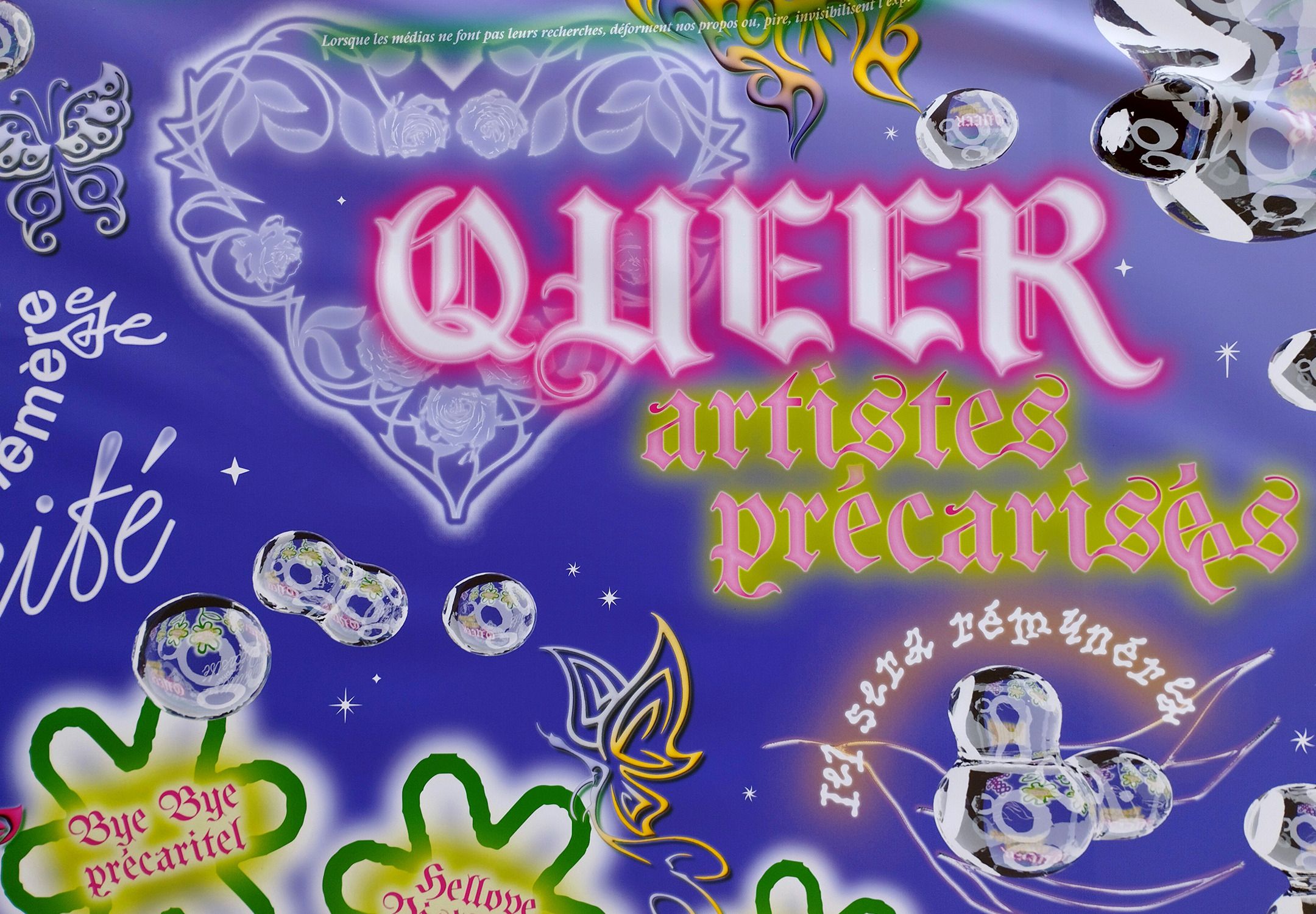 Vue rapprochée sur l'une des bâches. On lit, entre autres "queer artistes précarisé·es".